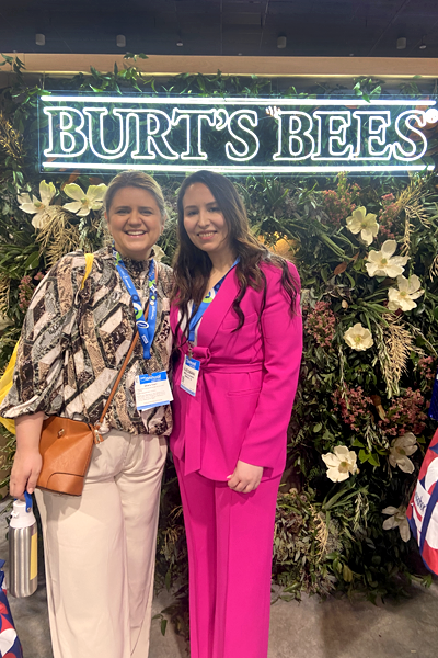 Two female residents indoors in front of a Burt's Bees neon sign