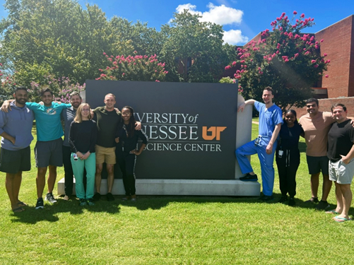 residents with coordinator outside by a UTHSC sign