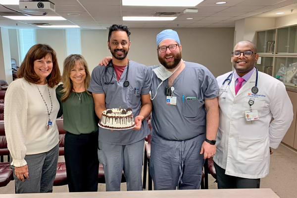 Faculty with resident holding his birthday cake