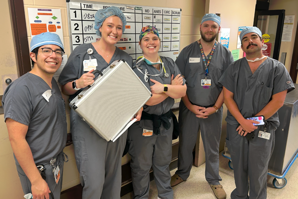 Five residents wearing scrubs in the hospital hallway