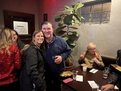 Two faculty hugging at the holiday party