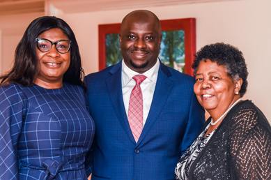 Two graduation ceremony attendees with program manager