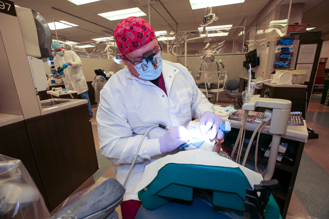 Endodontist working on patient with dental tool in the endodontics clinic.