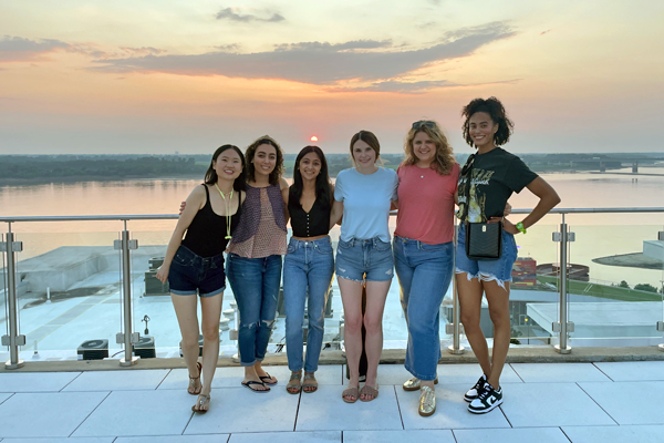 Six female residents on the outdoor patio at the top of the Bass Pro Pyramid with the sunset in the background