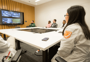 Residents around a table watching a monitor