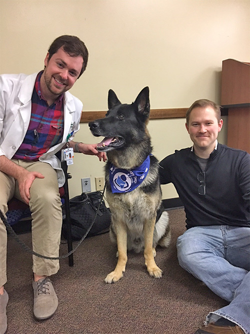 Two male residents with a therapy dog