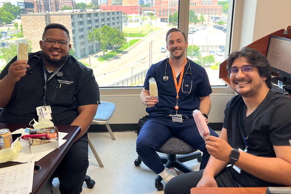 Three male residents sitting inside holding popsicles