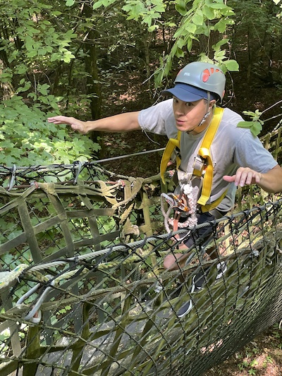 Resident walking a rope bridge outdoors