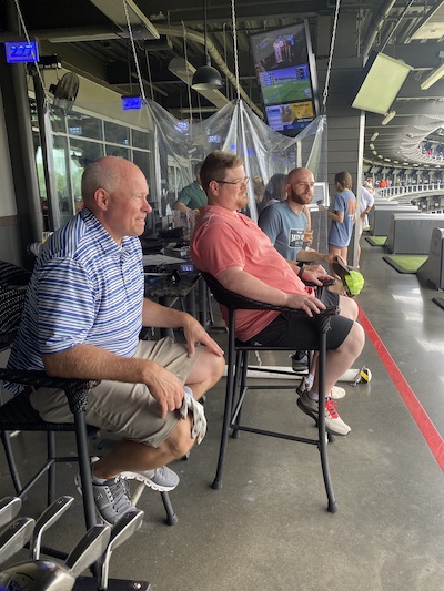 Program director and residents watching others at the golf range