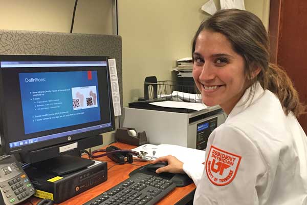 Smiling female resident sitting at a desk with a laptop computer