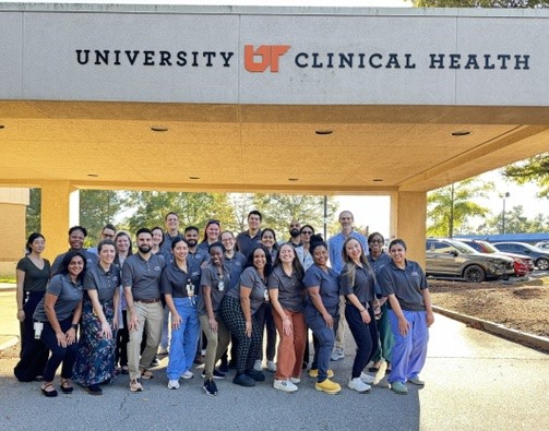 Residents outdoors in front of a UT Family Medicine sign
