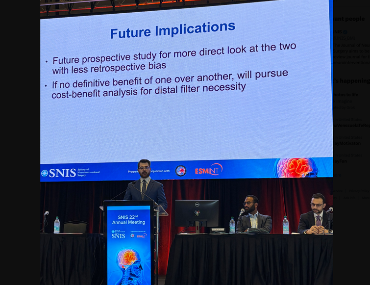 Resident giving a presentation on stage with a large screen showing the presentation behind him