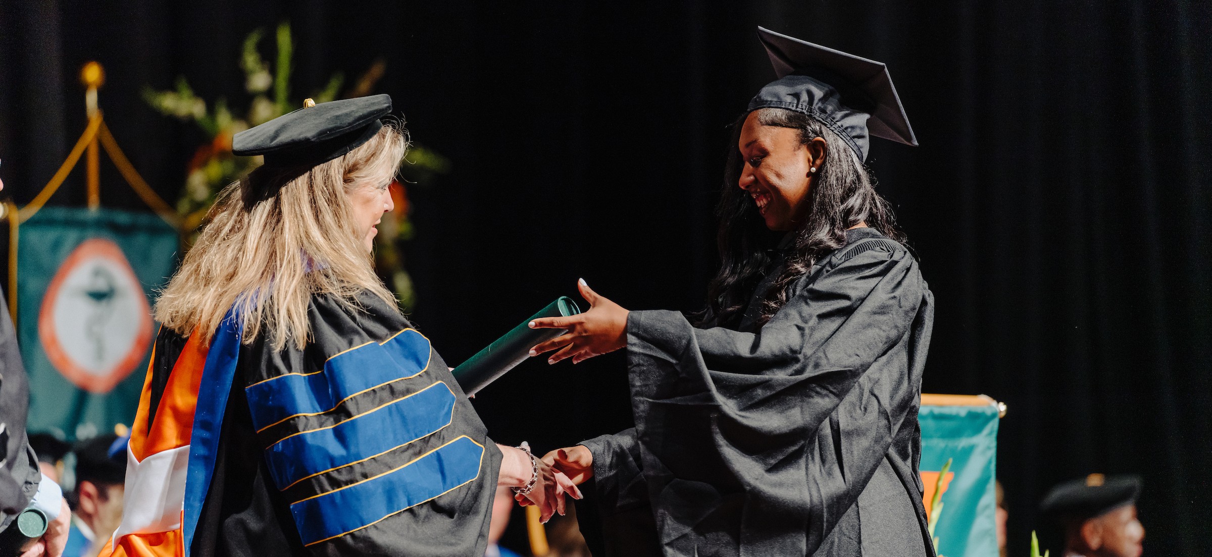 bsngradhero woman in graduation gown receiving nursing diploma