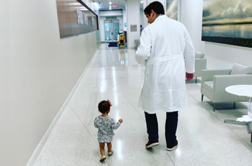 TDoctor and toddler walking down a hospital hallway