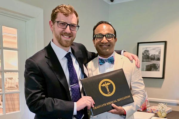 Male graduate holding his certificate while standing with program director