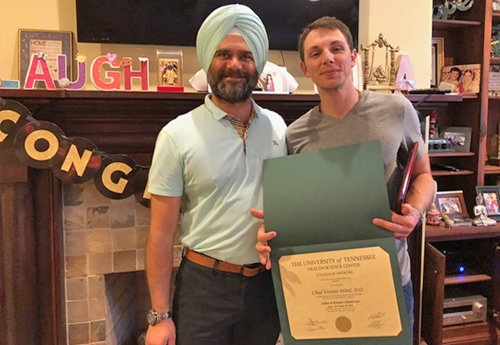 Fellow standing by a faculty member while holding a certificate 
