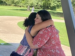 Two female residents hugging at graduation celebration outdoors