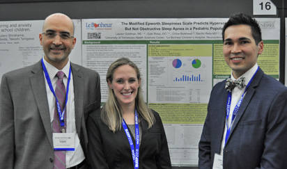 Two residents and faculty member before a poster presentation