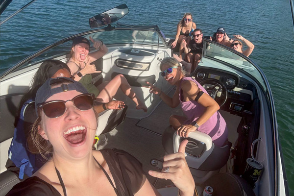 Group of fellows posing for a selfie while riding in a boat on a lake.
