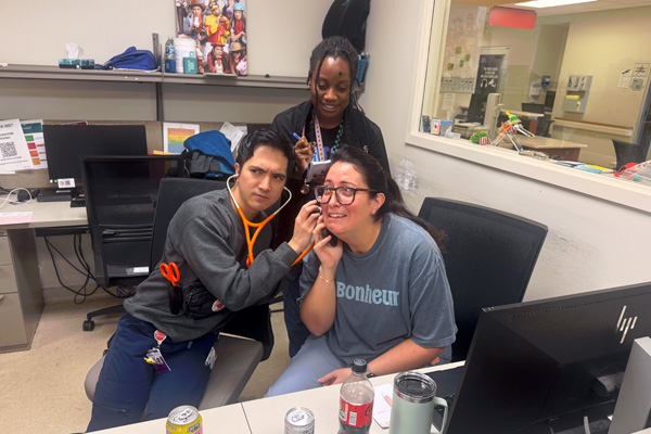 Three fellows in a hospital office participating in a playful activity at a workstation