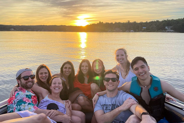 Group of fellows sitting together on a boat at sunset on a lake
