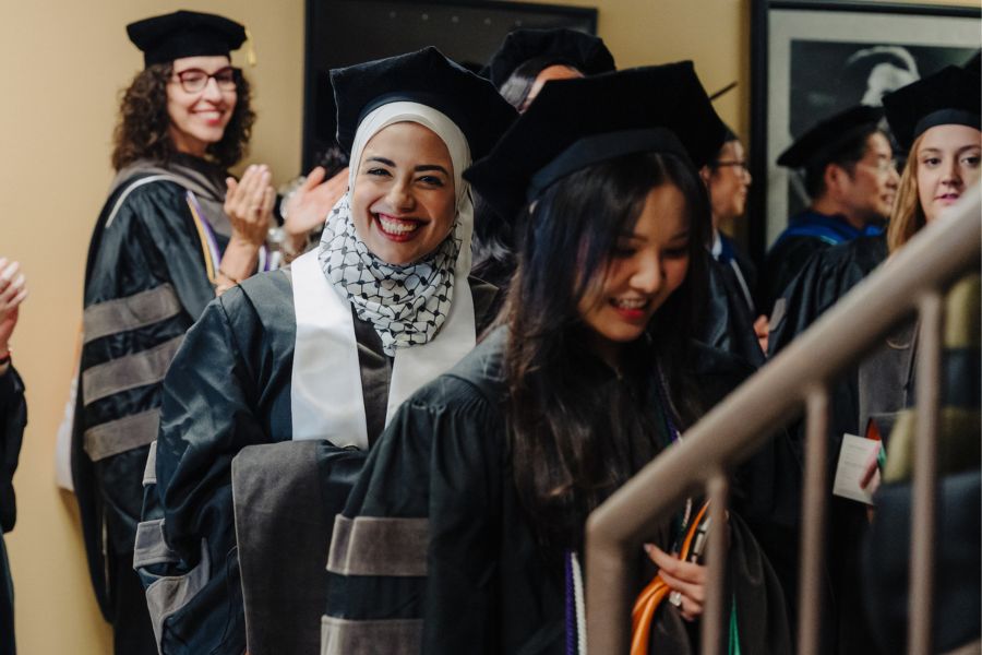 Student smiles in graduation attire at 2025 commencement.