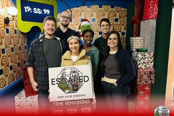 Group of six residents posing in a Christmas‑themed room after completing an escape challenge.
