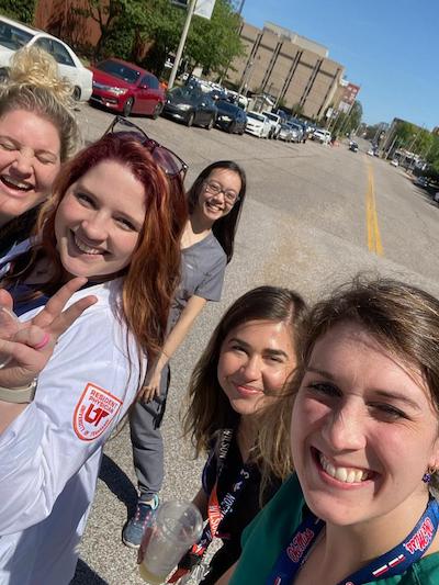 Five female fellows taking a selfie in the parking lot