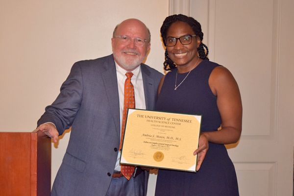 Graduate holding certificate with faculty member